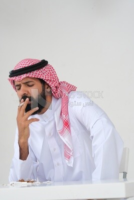 Saudi man wearing a white thobe and shemagh takes a deep breath from a cigarette, tobacco addiction, cigarette addiction, harmful and toxic substance abuse, harmful behavioral habits, no smoking, Saud