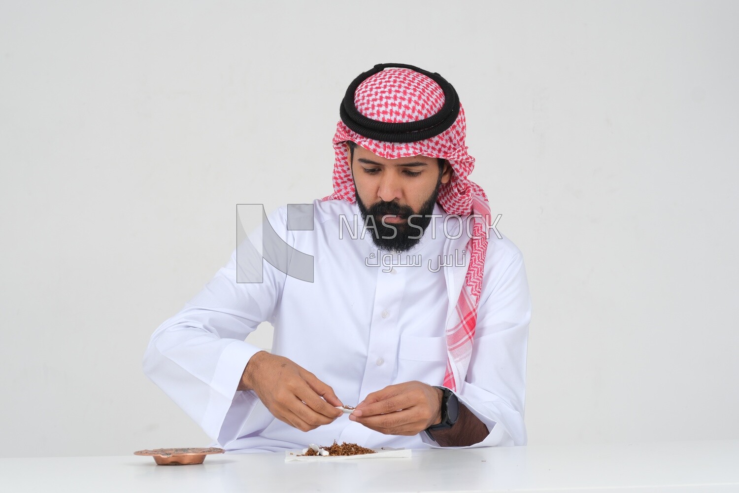 Saudi man wrapping cigarettes with his hands, tobacco addiction, cigarette addiction, harmful and toxic substance abuse, harmful behavioral habits, no smoking, Saudi model