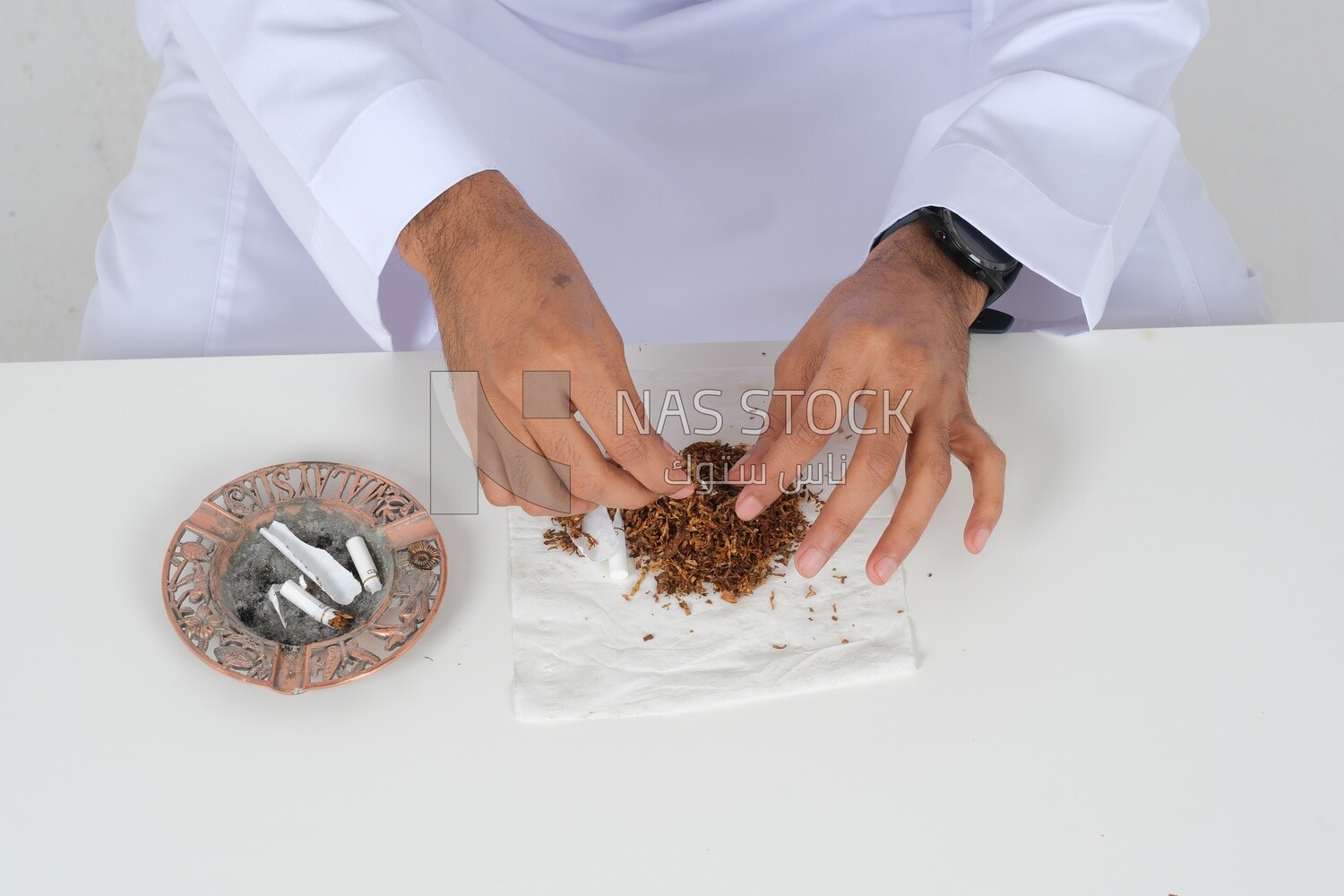 Saudi man wrapping cigarettes with his hands, tobacco addiction, cigarette addiction, harmful and toxic substance abuse, harmful behavioral habits, no smoking, Saudi model