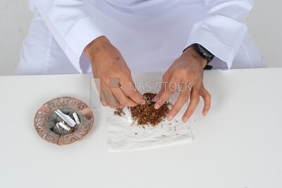 Saudi man wrapping cigarettes with his hands, tobacco addiction, cigarette addiction, harmful and toxic substance abuse, harmful behavioral habits, no smoking, Saudi model