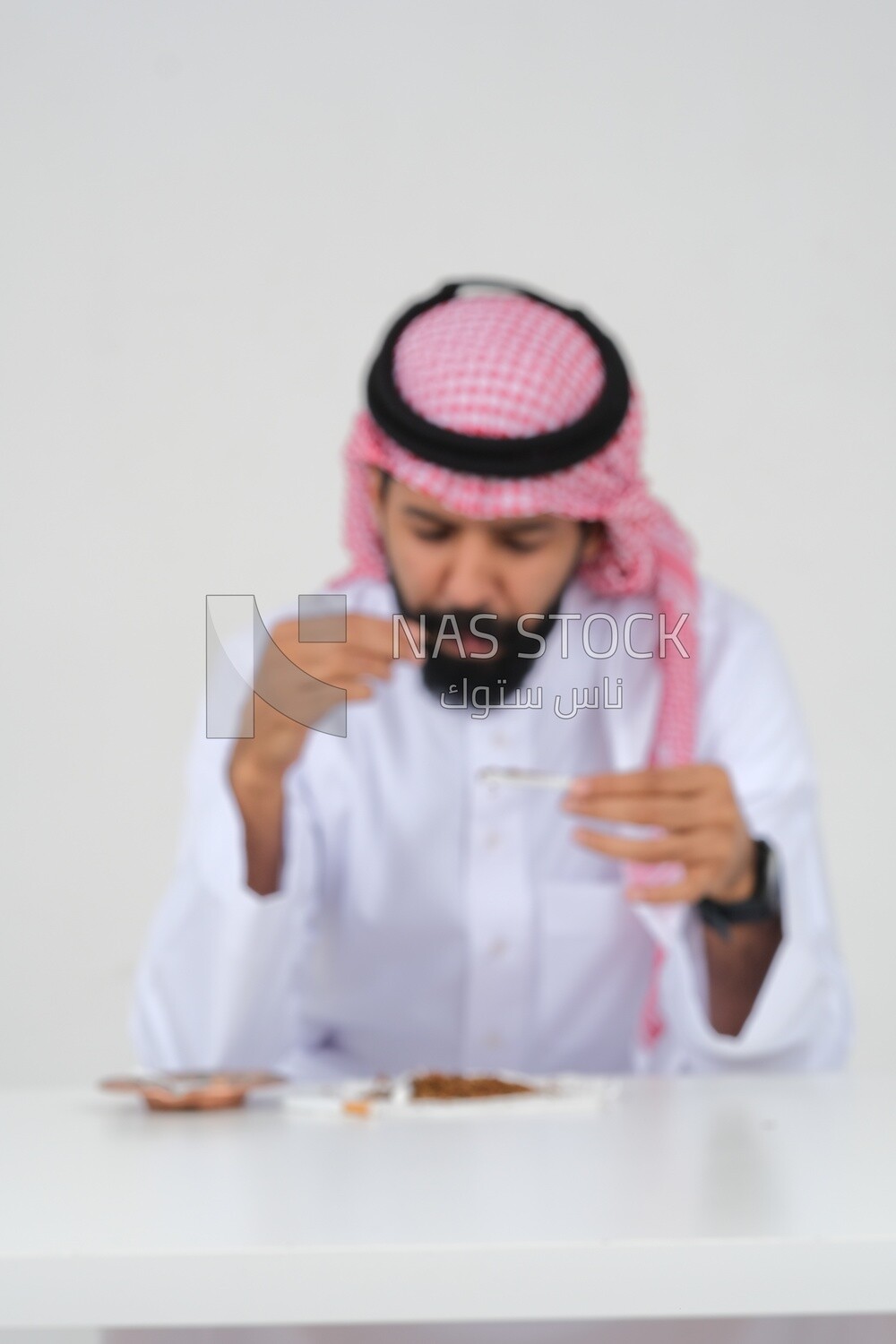 Saudi man wrapping cigarettes with his hands, tobacco addiction, cigarette addiction, harmful and toxic substance abuse, harmful behavioral habits, no smoking, Saudi model