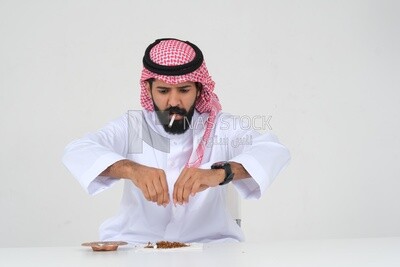 Saudi man wrapping cigarettes with his hands, tobacco addiction, cigarette addiction, harmful and toxic substance abuse, harmful behavioral habits, no smoking, Saudi model