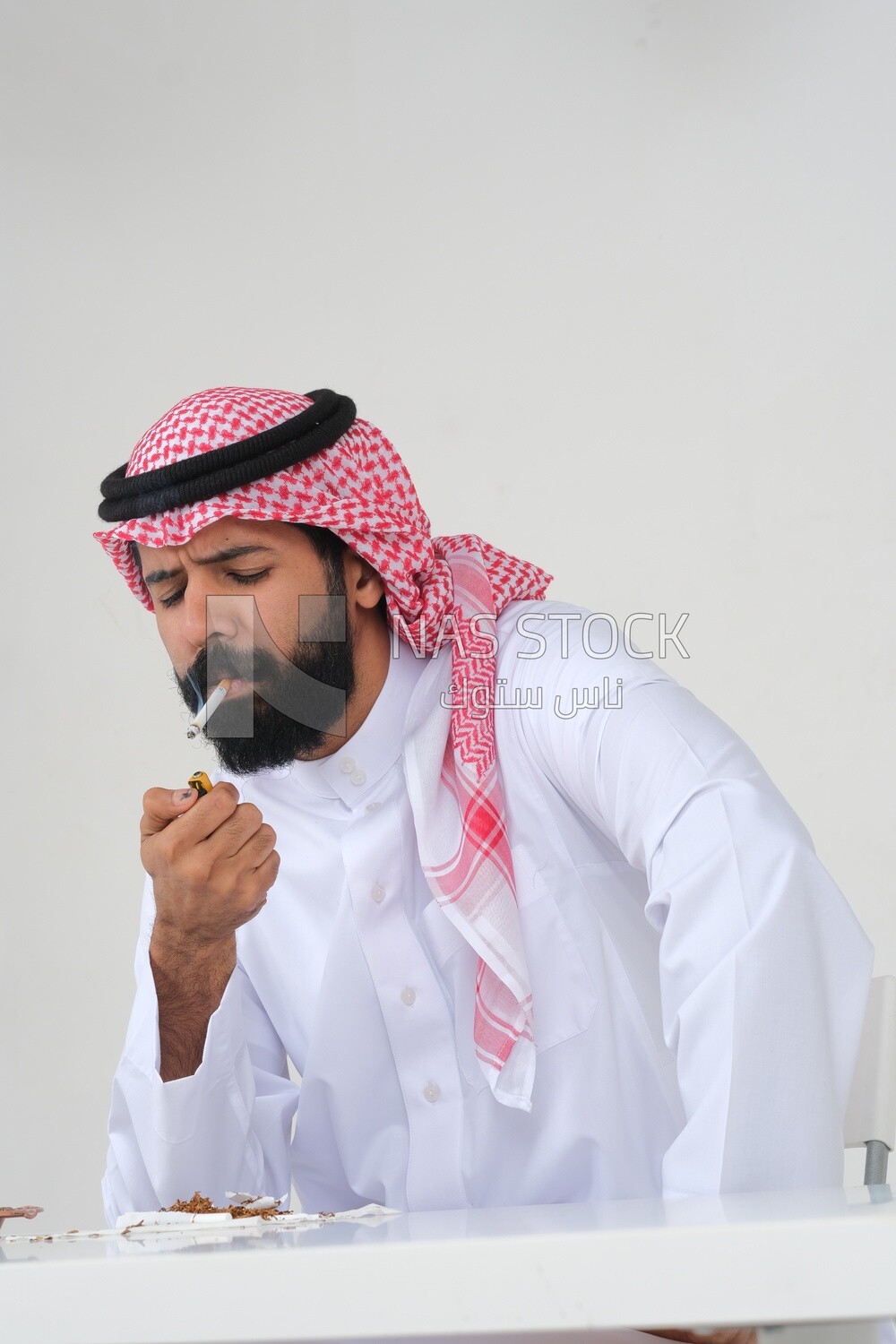 Saudi man wearing a white thobe and shemagh takes a deep breath from a cigarette, tobacco addiction, cigarette addiction, harmful and toxic substance abuse, harmful behavioral habits, no smoking, Saud