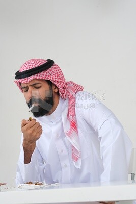 Saudi man wearing a white thobe and shemagh takes a deep breath from a cigarette, tobacco addiction, cigarette addiction, harmful and toxic substance abuse, harmful behavioral habits, no smoking, Saud