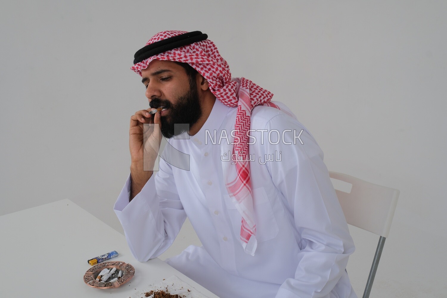 Saudi man wearing a white thobe and shemagh takes a deep breath from a cigarette, tobacco addiction, cigarette addiction, harmful and toxic substance abuse, harmful behavioral habits, no smoking, Saud