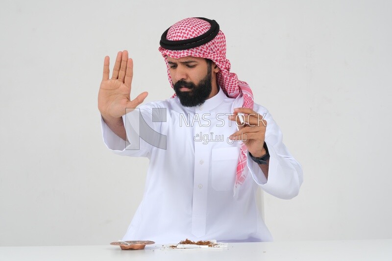 Saudi man fights against the smoking habit, gestures indicating stopping, tobacco addiction, cigarette addiction, harmful and toxic substance abuse, harmful behavioral habits, no smoking, Saudi model