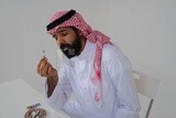 Saudi man wearing a white thobe and shemagh takes a deep breath from a cigarette, tobacco addiction, cigarette addiction, harmful and toxic substance abuse, harmful behavioral habits, no smoking, Saud