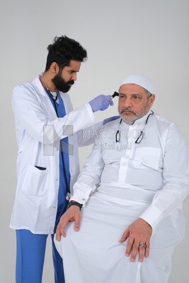 Saudi man wearing a medical coat and a stethoscope, checking the patient&#39;s ears, white background, medicine and health care, Saudi model