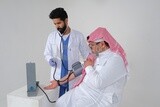 Saudi man wearing a medical coat and a stethoscope, measuring patient pressure, white background, medicine and health care, Saudi model