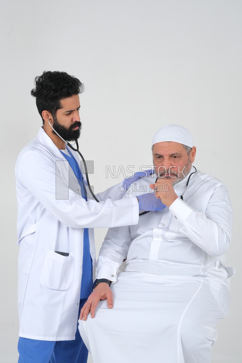 Saudi man wearing a medical coat and a stethoscope, the doctor listens to the patient&#39;s heartbeat, white background, medicine and health care, Saudi model