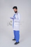 Saudi man wearing a medical coat and a stethoscope, holding a paper  to write a report on the patient&#39;s condition, white background, medicine and health care, Saudi model