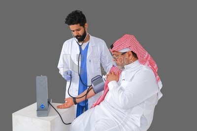 رجل سعودي يرتدي معطفا طبيا وسماعة طبية ، يقيس ضغط المريض ، الخلفية البيضاء ، الطب والرعاية الصحية ، موديل سعودي