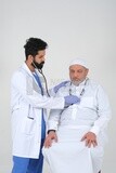 Saudi man wearing a medical coat and a stethoscope, the doctor listens to the patient&#39;s heartbeat, white background, medicine and health care, Saudi model