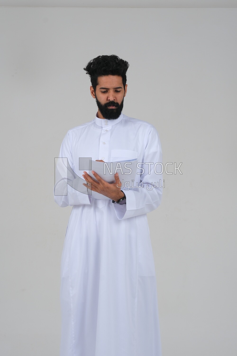 Saudi man taking notes on work papers and files, preparing reports and work tasks, business feasibility study, white background, Saudi model
