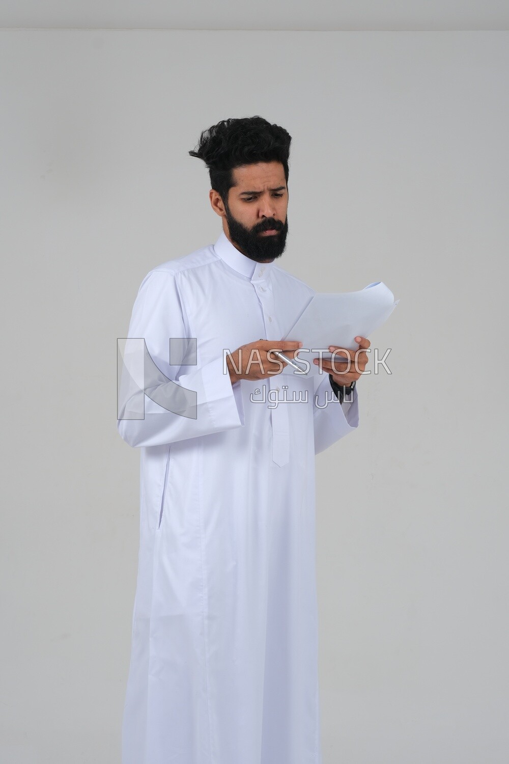 Saudi man taking notes on work papers and files, preparing reports and work tasks, business feasibility study, white background, Saudi model