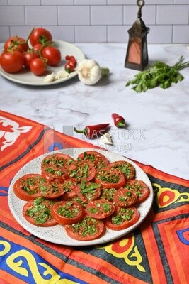 Plate of pickled tomatoes with parsley, besides garlic, red pepper, Egyptian pickles, Arab restaurants