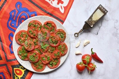 Plate of pickled tomatoes with parsley, besides garlic, red pepper, Egyptian pickles, Arab restaurants