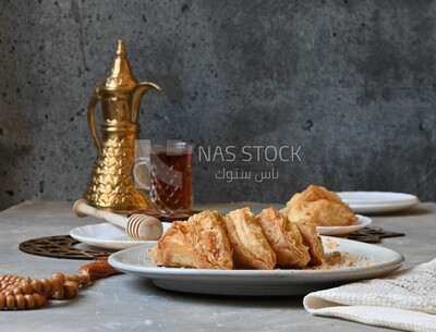 Baklava with cream in it, a cup of tea, a plate of honey, oriental Arabic sweets, Ramadan sweets