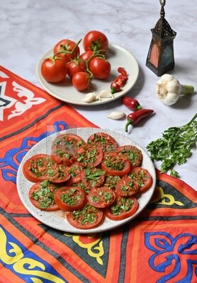 Plate of pickled tomatoes with parsley, besides garlic, red pepper, Egyptian pickles, Arab restaurants
