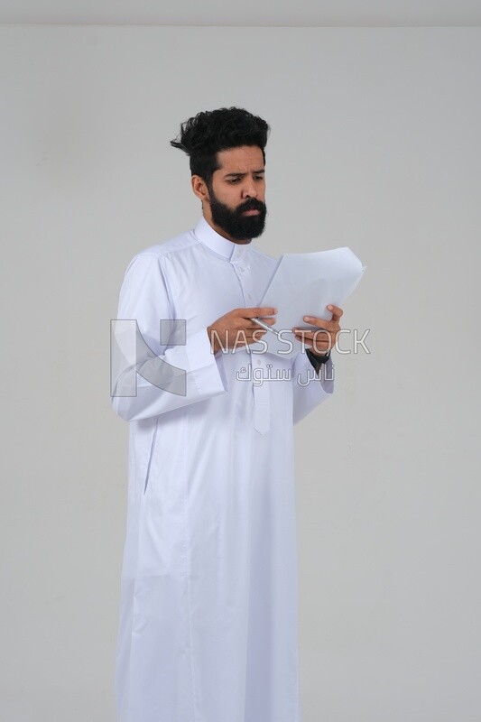 Saudi man taking notes on work papers and files, preparing reports and work tasks, business feasibility study, white background, Saudi model