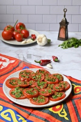 Plate of pickled tomatoes with parsley, besides garlic, red pepper, Egyptian pickles, Arab restaurants