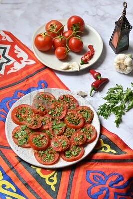 Plate of pickled tomatoes with parsley, besides garlic, red pepper, Egyptian pickles, Arab restaurants