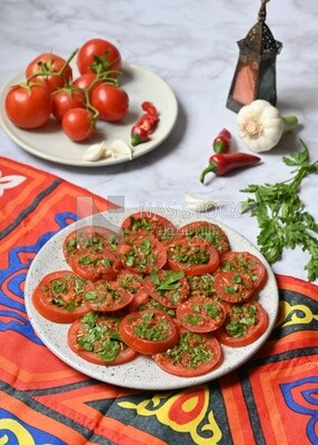 Plate of pickled tomatoes with parsley, besides garlic, red pepper, Egyptian pickles, Arab restaurants