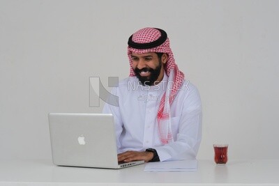 Saudi man sitting and working on a laptop, a cup of tea, business feasibility study, white background, Saudi model