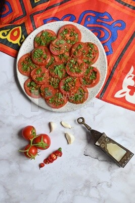 Plate of pickled tomatoes with parsley, besides garlic, red pepper, Egyptian pickles, Arab restaurants