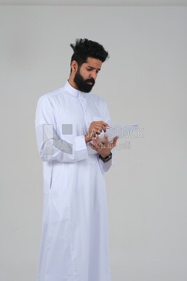 Saudi man taking notes on work papers and files, preparing reports and work tasks, business feasibility study, white background, Saudi model