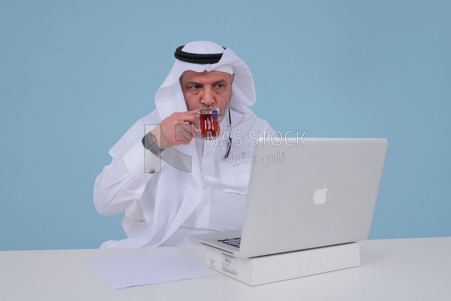 Saudi man sitting and working on a laptop, drinking a cup of tea, business feasibility study, Saudi model