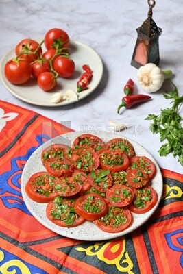Plate of pickled tomatoes with parsley, besides garlic, red pepper, Egyptian pickles, Arab restaurants