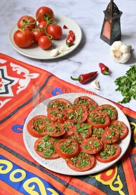 Plate of pickled tomatoes with parsley, besides garlic, red pepper, Egyptian pickles, Arab restaurants