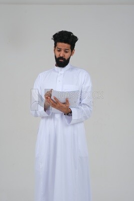 Saudi man taking notes on work papers and files, preparing reports and work tasks, business feasibility study, white background, Saudi model