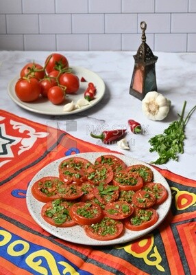 Plate of pickled tomatoes with parsley, besides garlic, red pepper, Egyptian pickles, Arab restaurants