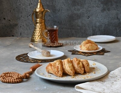Baklava with cream in it, a cup of tea, a plate of honey, oriental Arabic sweets, Ramadan sweets