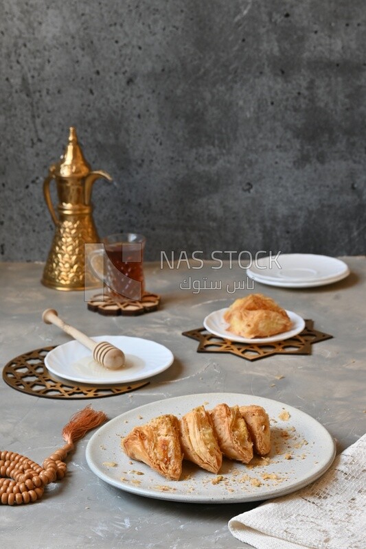 Baklava with cream in it, a cup of tea, a plate of honey, oriental Arabic sweets, Ramadan sweets