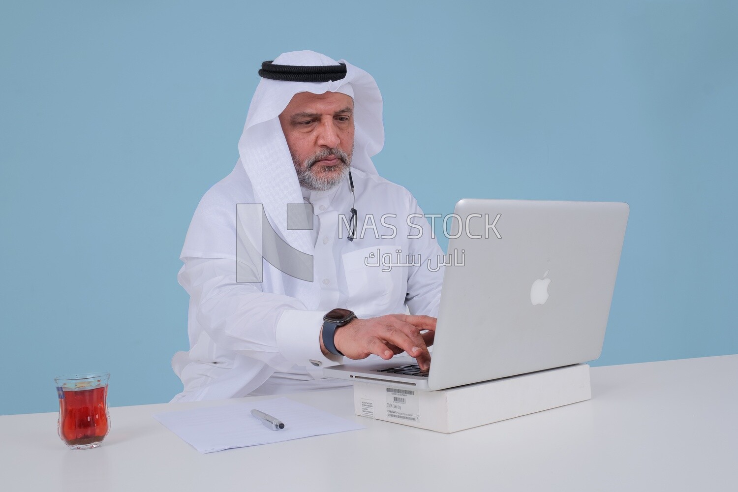 Saudi man sitting and working on a laptop, a cup of tea, business feasibility study, Saudi model