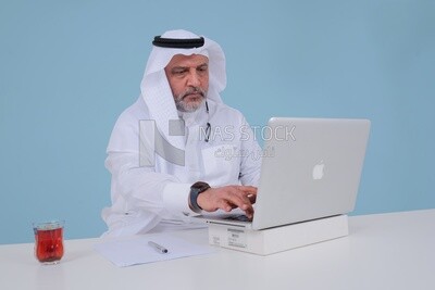 Saudi man sitting and working on a laptop, a cup of tea, business feasibility study, Saudi model