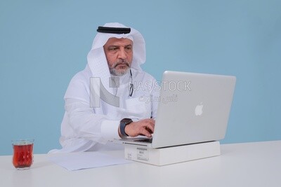 Saudi man sitting and working on a laptop, a cup of tea, business feasibility study, Saudi model