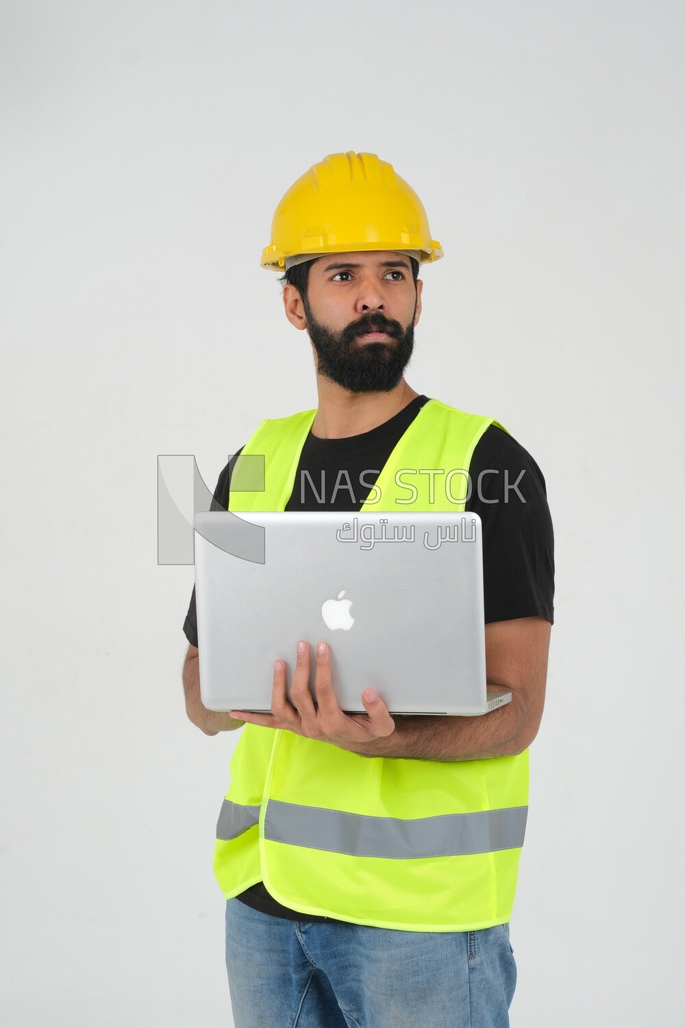 Saudi engineer wearing a work helmet and protective jacket, holding a laptop and looking away, engineering professions and jobs, white background, Saudi model