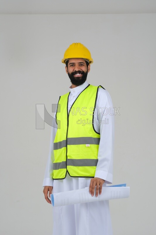 saudi engineer wearing a work hat and safety vest, holding in his hand