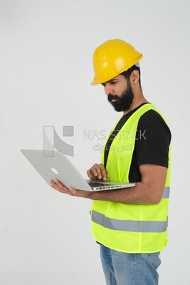 Saudi engineer wearing a work helmet and protective jacket, holding a laptop and looking away, engineering professions and jobs, white background, Saudi model