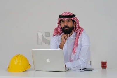 Saudi engineer, sitting and working on the laptop, a cup of tea, work hat, engineering professions and jobs, white background, Saudi model