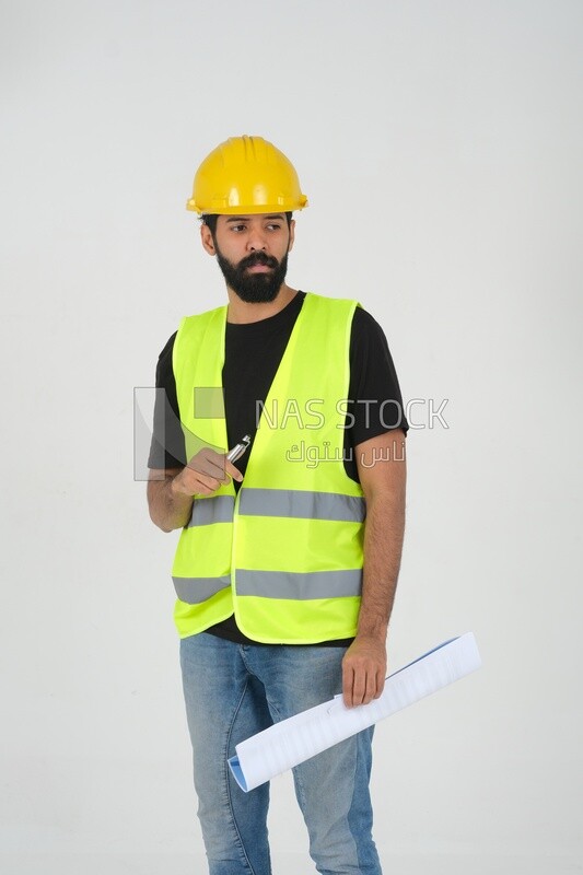 Saudi engineer wearing a work hat and safety vest, holding in his hand
