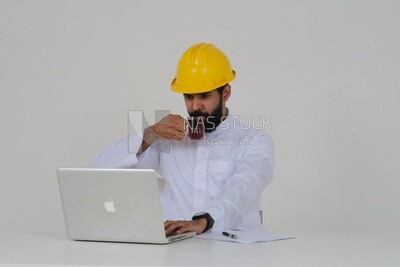 Saudi engineer wearing a work hat sitting and working on the laptop, drinking a cup of tea, engineering professions and jobs, white background, Saudi model