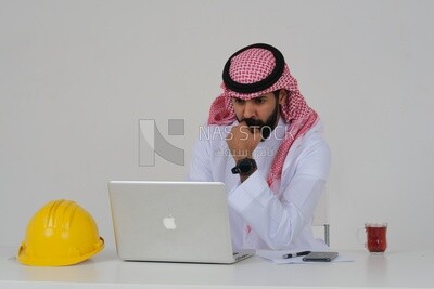 Saudi engineer, sitting and working on the laptop, a cup of tea, work hat, engineering professions and jobs, white background, Saudi model