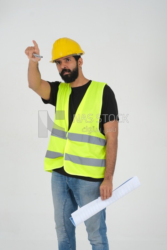 Saudi engineer wearing a work hat and safety vest, holding in his hand the construction plan pointing away, engineering professions and jobs, white background, Saudi model