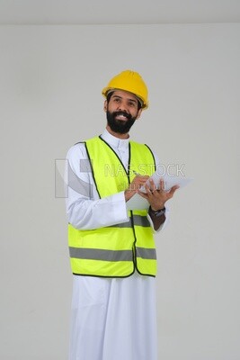 Saudi engineer wearing a work helmet and protective jacket, writing and taking notes, engineering professions and jobs, white background, Saudi model