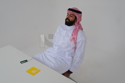 Saudi man wearing a white thobe and shemagh exposed to loss of consciousness as a result of using drugs, drug abuse and white powder, Saudi model